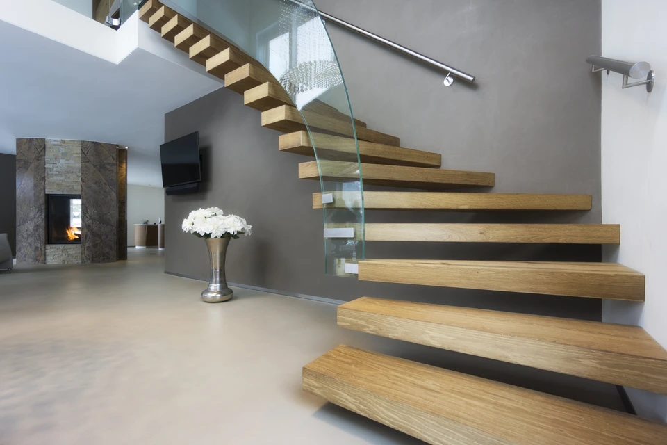 Intérieur moderne avec escalier suspendu à marches en bois massif et garde-corps en verre transparent