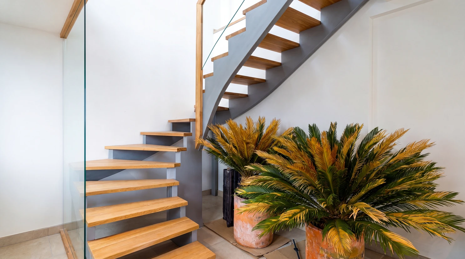Escalier intérieur moderne à double quart tournant, marches en chêne massif naturel fixées sur limon central métallique noir