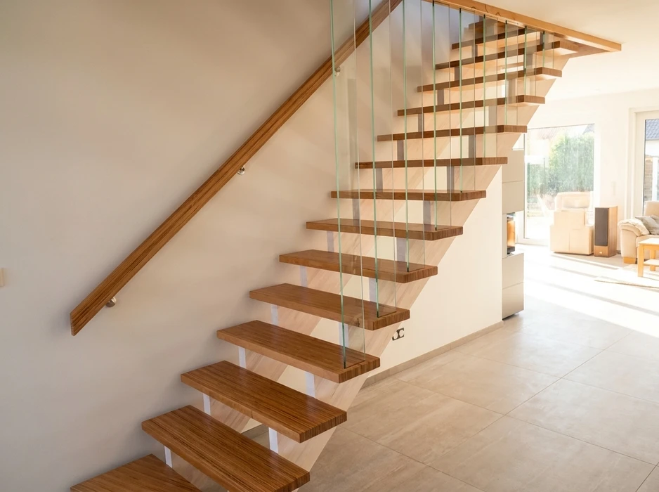 Escalier en bois massif vu de dessus, encadré d'une rambarde en verre trempé à joints noirs, menant à une cave en pierre apparente