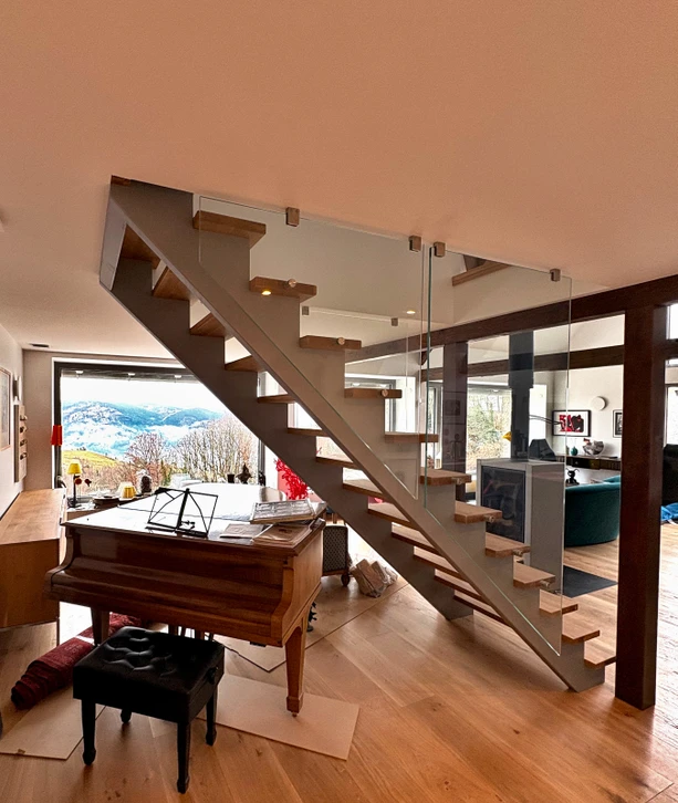 Escalier intérieur moderne en bois avec rampes métalliques en acier inoxydable fixées aux murs blancs
